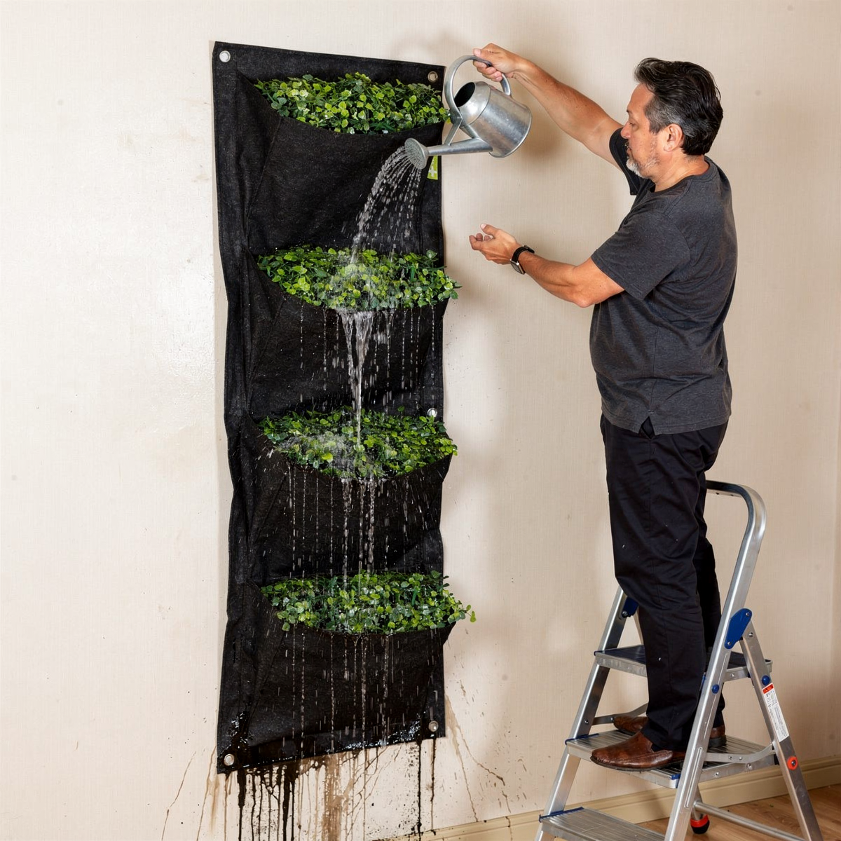 Entretien d'un mur végétal intérieur avec jardinière verticale suspendue nécessitant un escabeau.